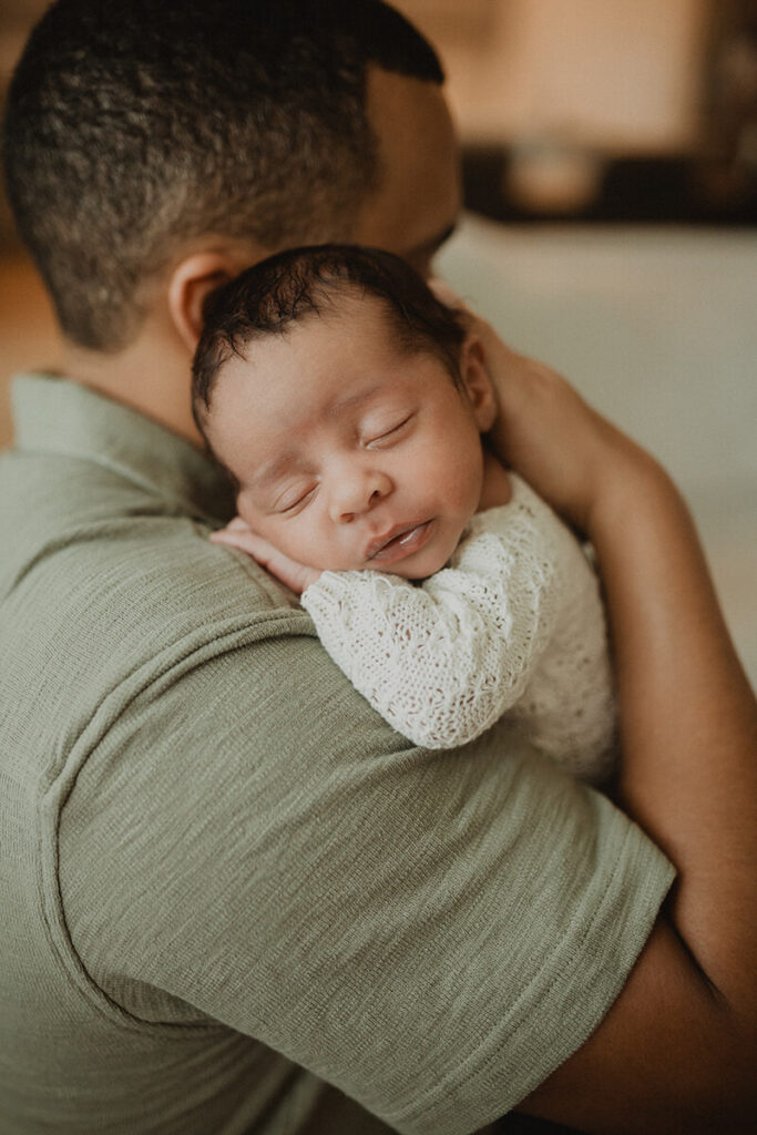 Father holding a sleeping newborn boy during an in-home lifestyle newborn session in Raleigh, North Carolina with Victoria Vasilyeva Photography.