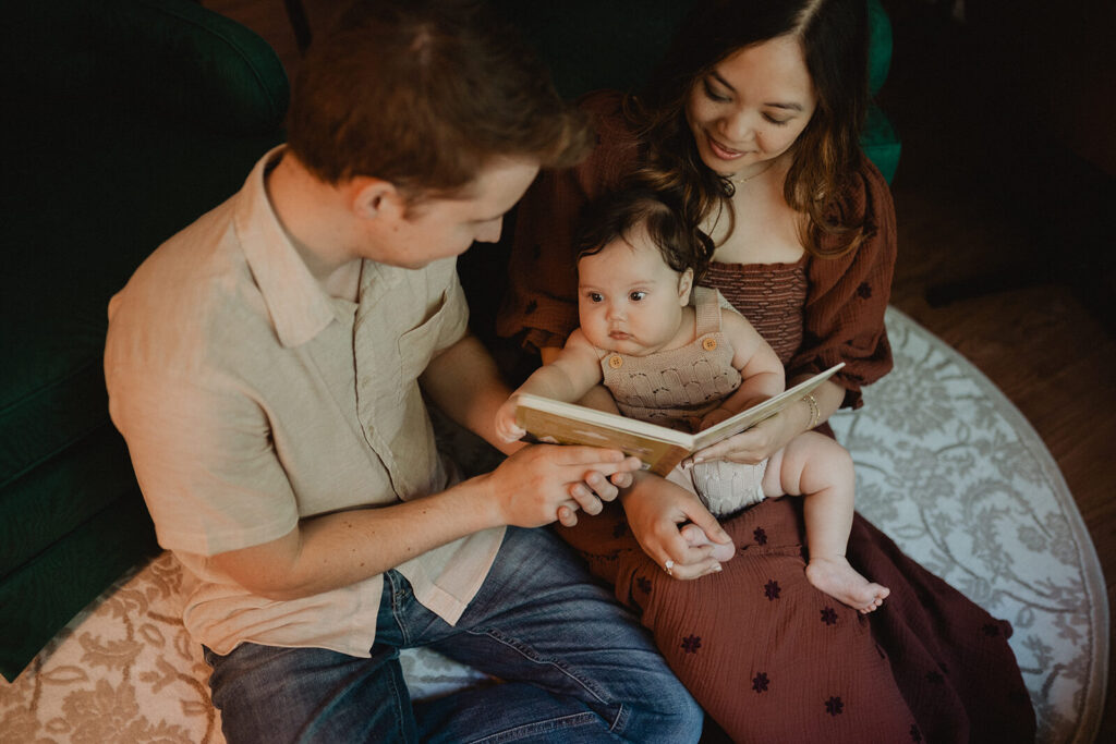 Parents reading a book with their curious baby boy during a cozy family moment at home.