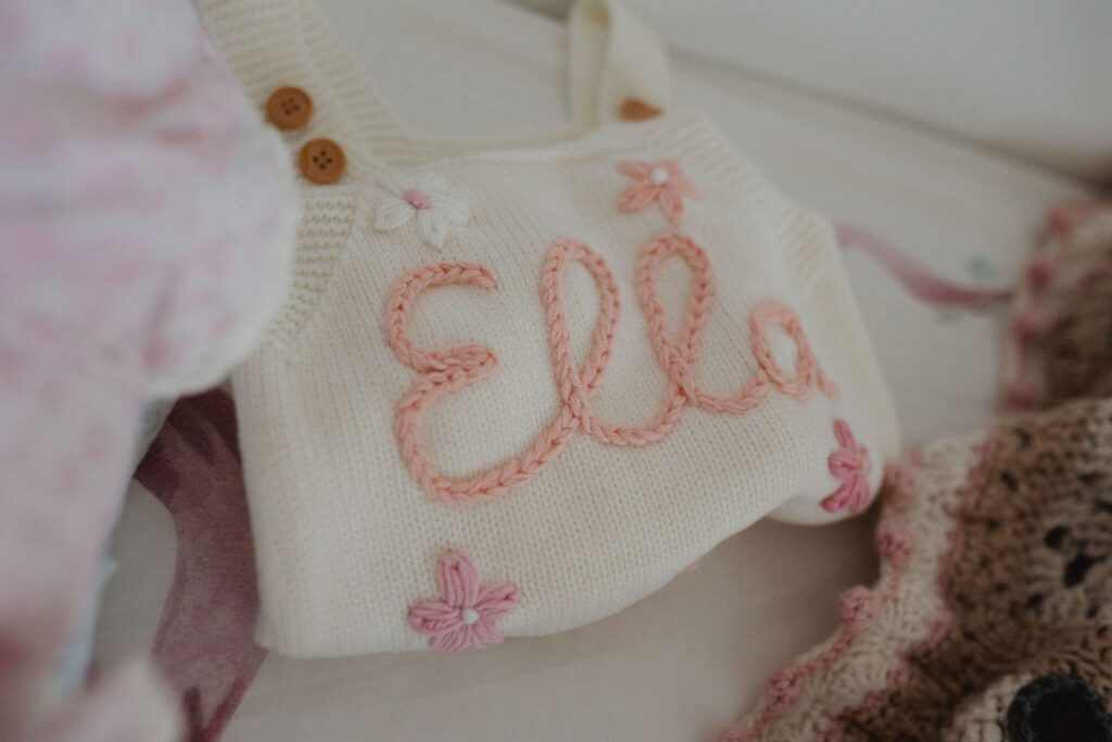 Personalized knitted baby romper with the name Ella photographed during a Raleigh NC newborn session at home.