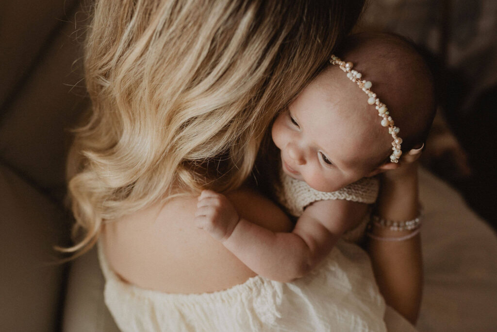 Mother holding her newborn baby girl during an intimate in-home newborn photography session in Raleigh NC.