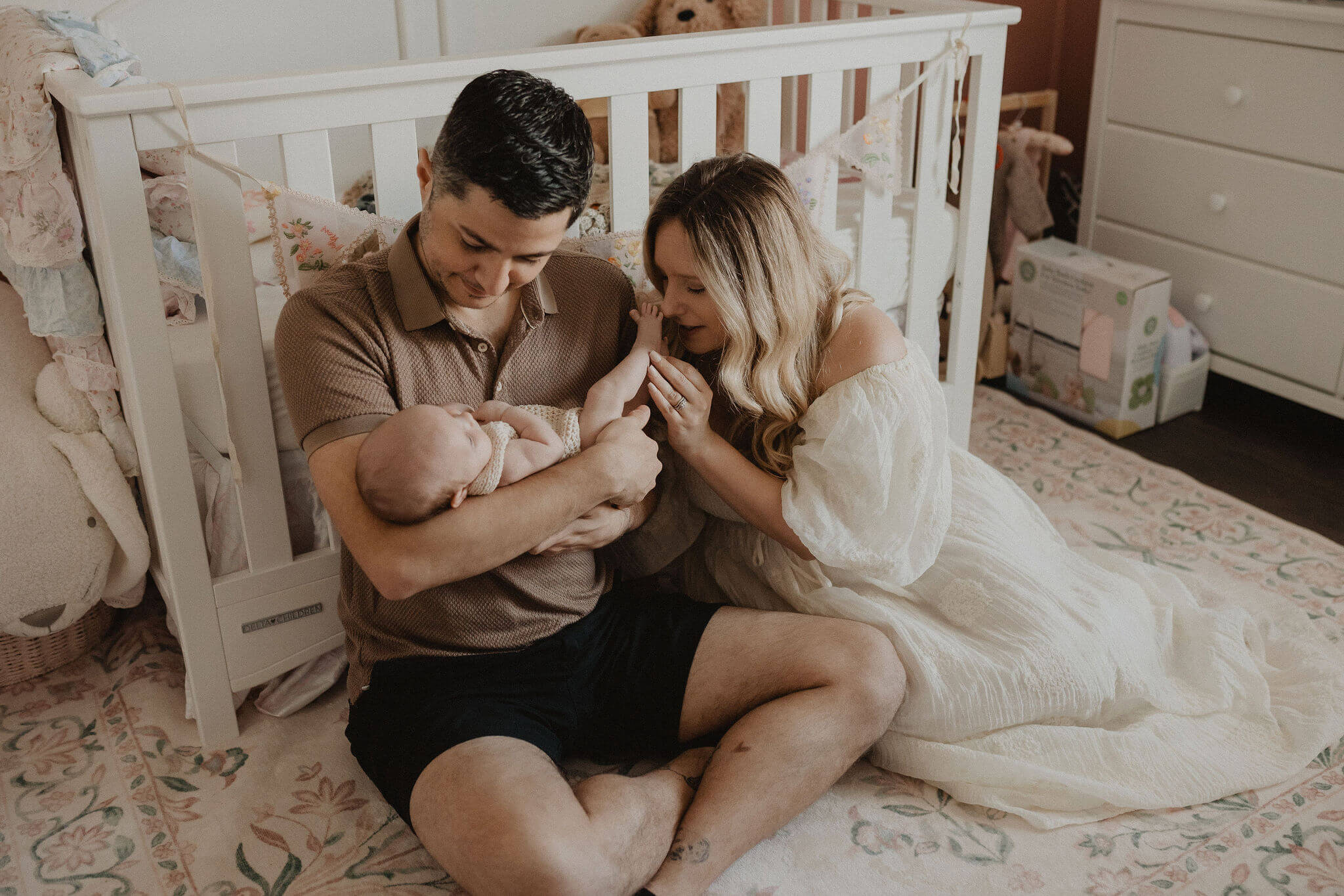 Parents with their baby girl in her nursery during an in-home newborn session by Victoria Vasilyeva Photography in Raleigh NC.