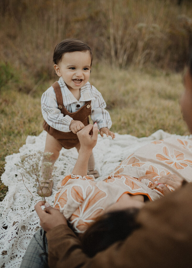 Smiling baby playing with his mother during a candid fall family photo session at Phillips Farms of Cary.