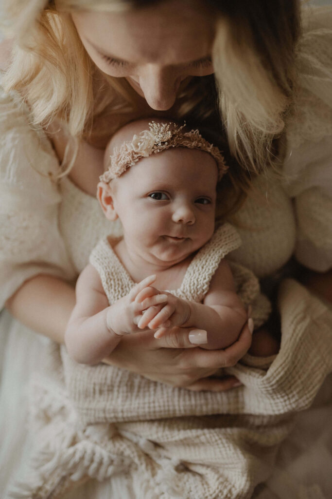 Mother holding her newborn baby girl in a soft neutral nursery during an in-home newborn session by Victoria Vasilyeva Photography, newborn photographer in Raleigh NC.