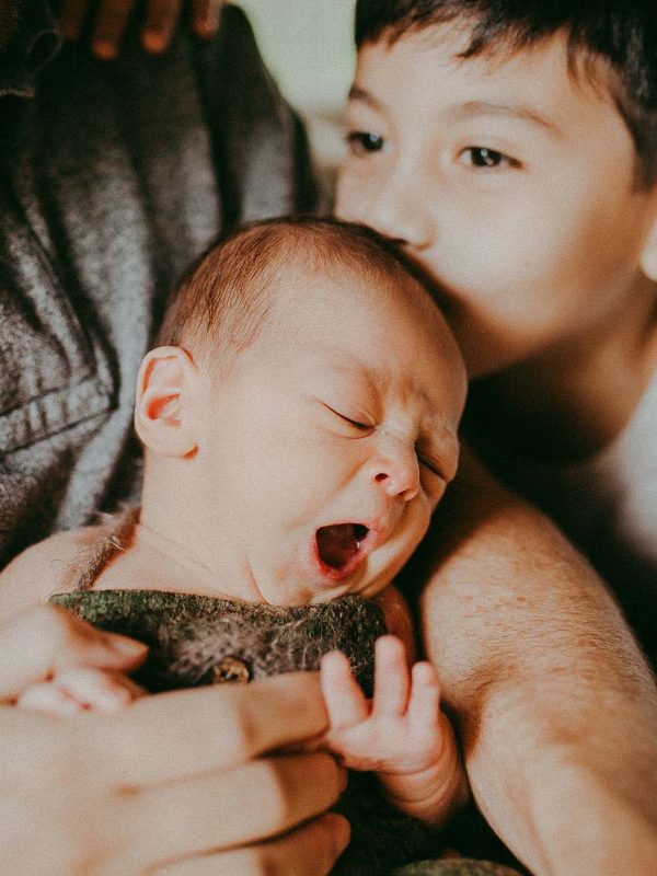 newborn baby boy yawns in daddy's arm