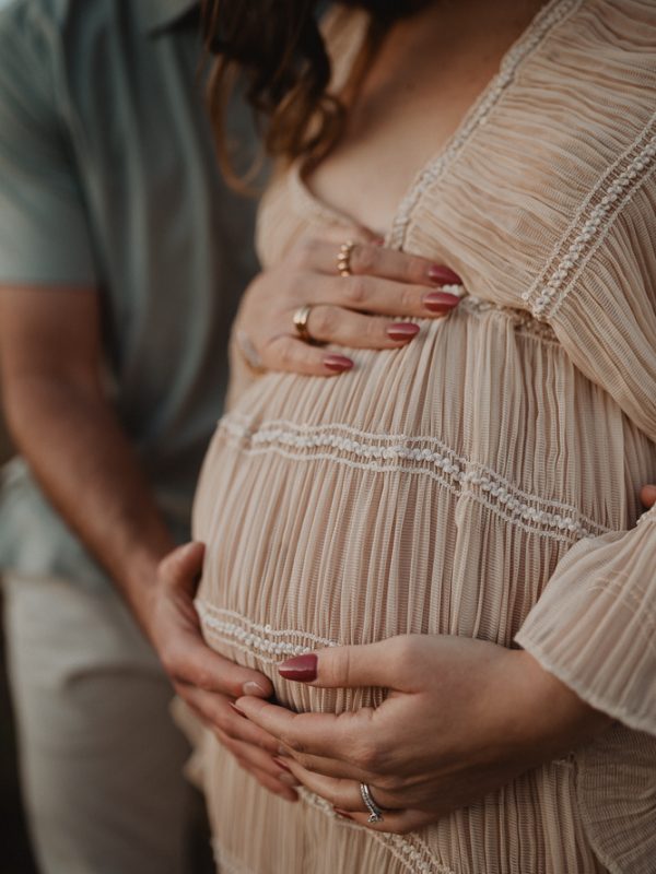 Close-up maternity photo of expecting parents’ hands resting on a baby bump during an outdoor maternity session in Raleigh, NC. Intimate maternity photography by Victoria Vasilyeva Photography.