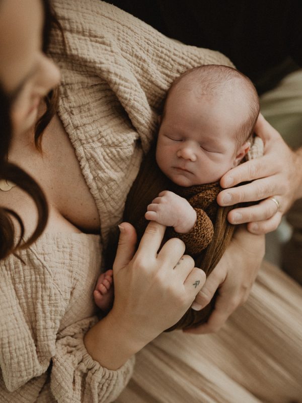Newborn baby boy sleeping peacefully on a mom’s chest during a cozy in-home newborn photo session in Raleigh, North Carolina. Newborn photography by Victoria Vasilyeva Photography.