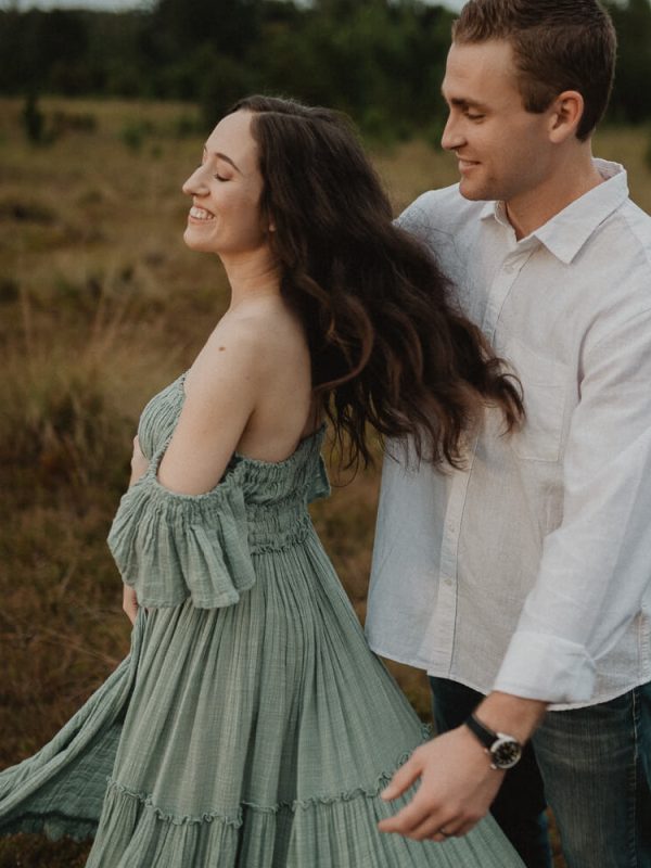 Mom and dad dancing in the field, smiling and holding each other during golden hour. Photo by Victoria Vasilyeva Photography – family photography in Raleigh, NC.