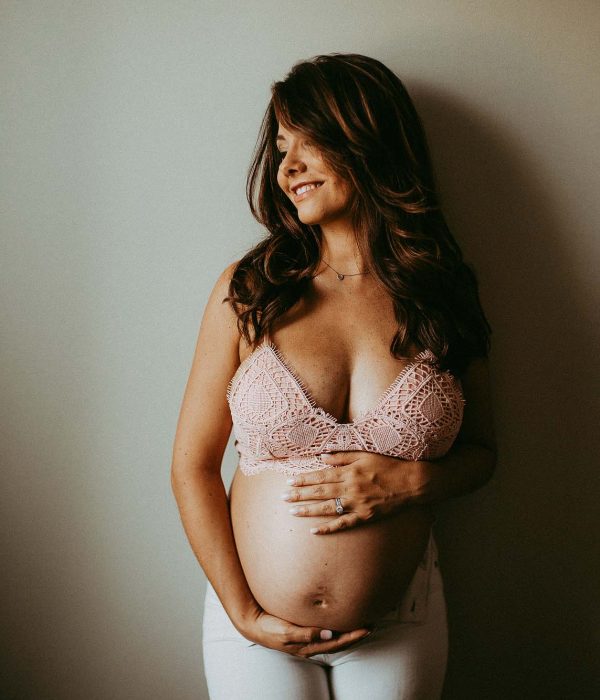mom-to-be in boho crochet bra smiling and holding her belly