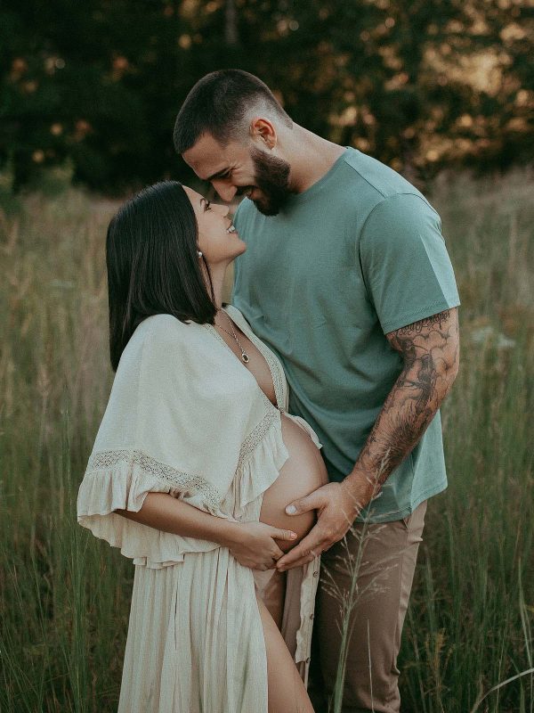 Expectant couple embracing in an idyllic Raleigh setting, showcasing their love and anticipation. Photo session took plave at Anderson point park by Victoria Vasilyeva Photography.