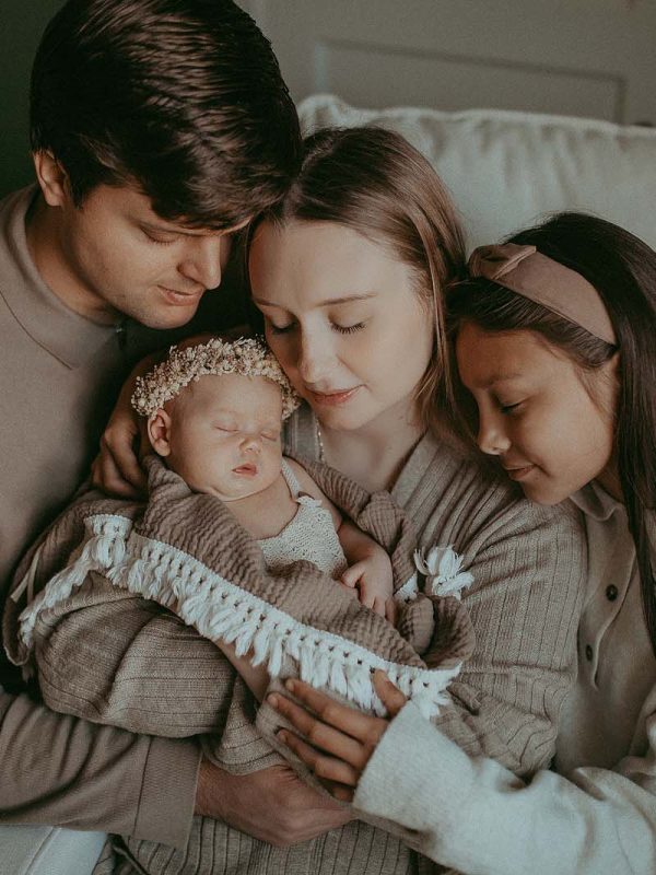family of 4 with neaborn baby girl pose to raleigh newborn photographer at home